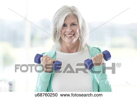 Stock Image - Senior woman using weights. Fotosearch