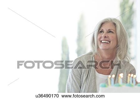 Stock Image - Senior woman with birthday cake. Fotosearch