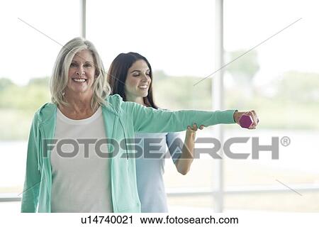 Stock Image - Senior woman with personal trainer. Fotosearch