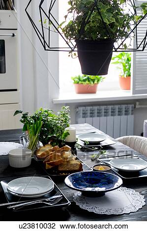 Stock Image - Set kitchen table with bread slices, fresh herbs and spring onions. Fotosearch