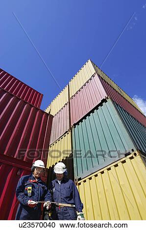 Stock Image - Shipping workers with cargo containers. Fotosearch