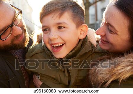 Stock Image - Smiling boy between mid adult parents. Fotosearch