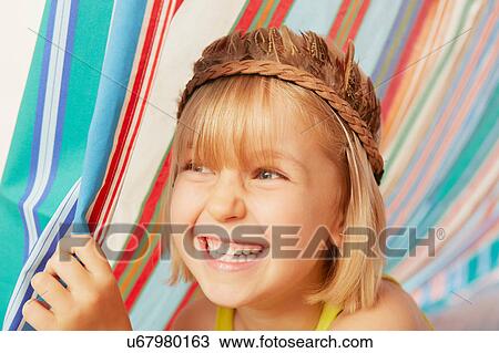 Stock Image - Smiling girl peeking out from striped tent. Fotosearch
