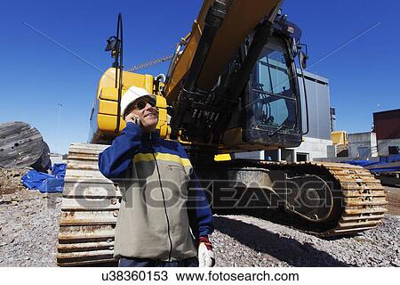 Stock Image - Surveyor on construction site with bulldozer. Fotosearch