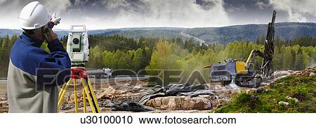 Stock Image - Surveyor on site with theodolite. Fotosearch