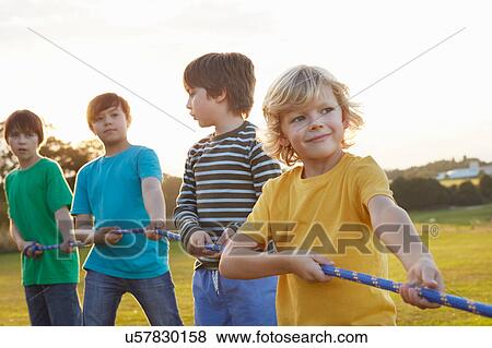 Stock Photo - Team of four boys preparing for tug o'war on playing field. Fotosearch
