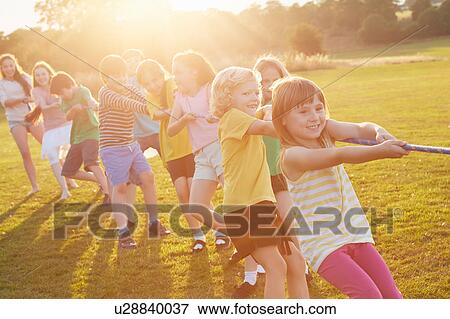 Stock Photo - Team of girls and boys pulling for tug o'war on playing field. Fotosearch