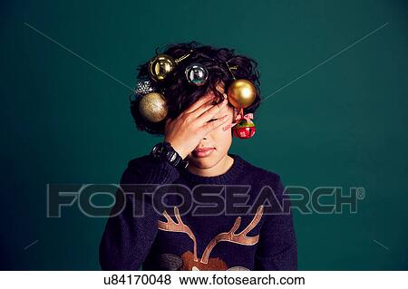 Teenage boy wearing Christmas jumper, and baubles in hair, covering face with hand View Large Photo Image Stock Photo - Teenage boy wearing Christmas jumper, and baubles in hair, covering face with hand. Fotosearch