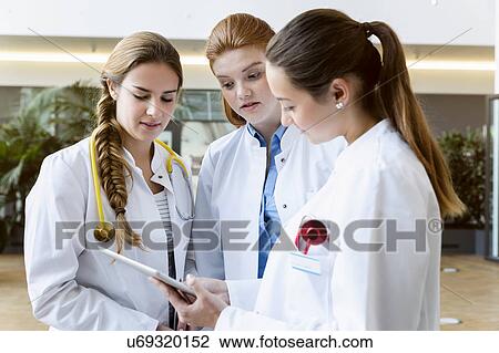 Three doctors looking at digital tablet View Large Photo Image Stock Image - Three doctors looking at digital tablet. Fotosearch