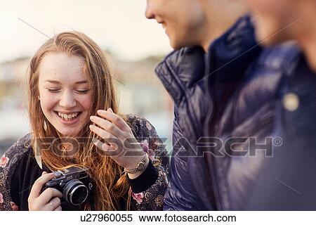 Three friends outdoors, young woman holding camera, laughing, Bristol, UK View Large Photo Image Stock Photography - Three friends outdoors, young woman holding camera, laughing, Bristol, UK. Fotosearch