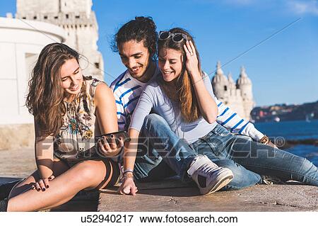 Three friends, sitting on wall by sea, Belem Tower in background, Lisbon, Portugal View Large Photo Image Stock Photo - Three friends, sitting on wall by sea, Belem Tower in background, Lisbon, Portugal. Fotosearch