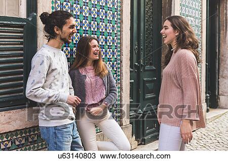 Stock Image - Three friends, standing in street, laughing, Lisbon, Portugal. Fotosearch