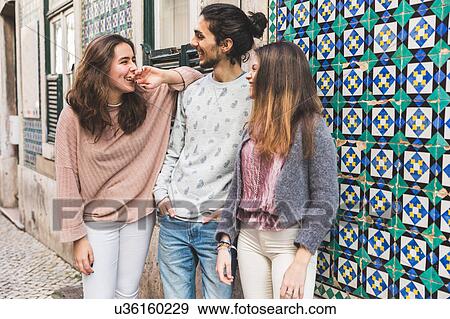 Stock Photo - Three friends, standing in street, laughing, Lisbon, Portugal. Fotosearch