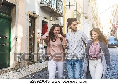Stock Image - Three friends walking along street, Lisbon, Portugal. Fotosearch