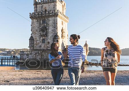 Stock Photo - Three friends, walking on beach, Belem Tower in background, Lisbon, Portugal. Fotosearch