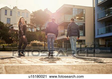 Stock Image - Three friends walking outdoors, young woman looking over shoulder, Bristol, UK. Fotosearch