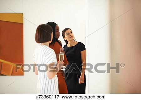 Three women looking at oil paintings at art gallery opening View Large Photo Image Stock Photo - Three women looking at oil paintings at art gallery opening. Fotosearch