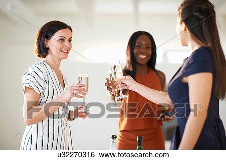 Three women raising a white wine toast at art gallery opening View Large Photo Image Stock Photograph - Three women raising a white wine toast at art gallery opening. Fotosearch