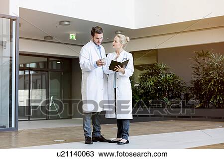 Two doctors having discussion, holding smartphone and diary View Large Photo Image Stock Image - Two doctors having discussion, holding smartphone and diary. Fotosearch