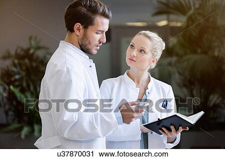 Two doctors having discussion, holding smartphone and diary View Large Photo Image Stock Image - Two doctors having discussion, holding smartphone and diary. Fotosearch