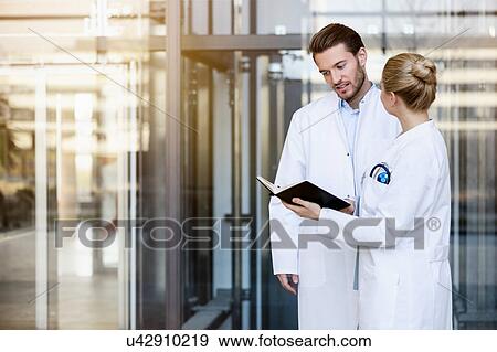 Two doctors having discussion, looking at diary View Large Photo Image Stock Photo - Two doctors having discussion, looking at diary. Fotosearch