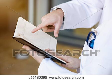 Two doctors looking at diary, mid section, close-up View Large Photo Image Stock Photography - Two doctors looking at diary, mid section, close-up. Fotosearch