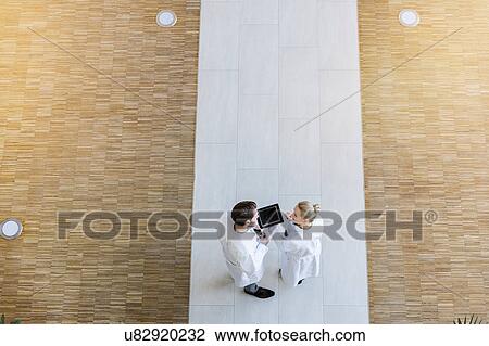 Two doctors looking at digital tablet, overhead view View Large Photo Image Stock Image - Two doctors looking at digital tablet, overhead view. Fotosearch