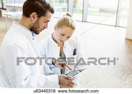 Two doctors looking at digital tablet View Large Photo Image Stock Photo - Two doctors looking at digital tablet. Fotosearch