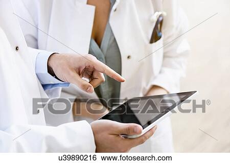 Two doctors looking at digital tablet, mid section, close-up View Large Photo Image Stock Photograph - Two doctors looking at digital tablet, mid section, close-up. Fotosearch