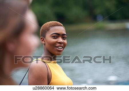 Picture - Two female friends outdoors, beside river. Fotosearch