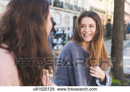 Stock Photography - Two female friends, sitting together, outdoors, Lisbon, Portugal. Fotosearch