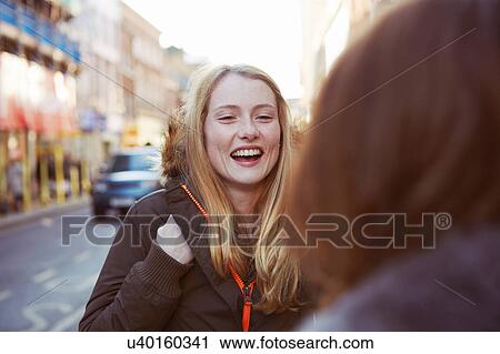 Stock Image - Two female friends talking in street. Fotosearch