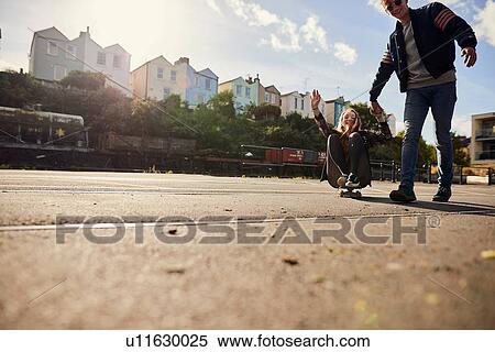 Two friends fooling around, young man pulling young woman along on skateboard, Bristol, UK View Large Photo Image Stock Photography - Two friends fooling around, young man pulling young woman along on skateboard, Bristol, UK. Fotosearch