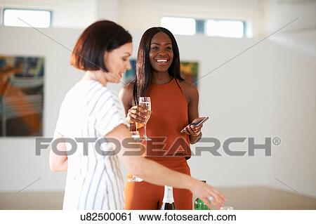 Stock Image - Two women at art gallery opening. Fotosearch