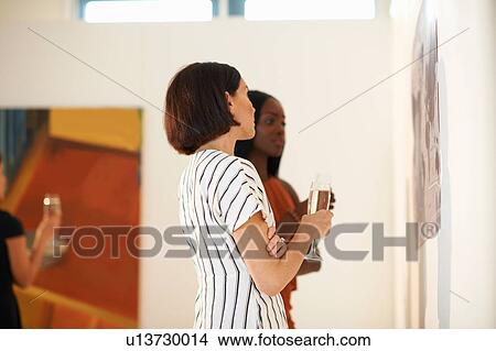 Two women looking at oil paintings at art gallery opening View Large Photo Image Picture - Two women looking at oil paintings at art gallery opening. Fotosearch