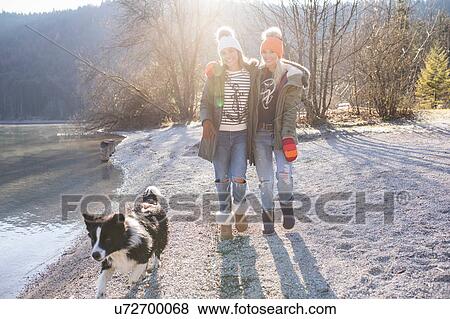 Two women walking dog on lakeside in Bavarian Alps View Large Photo Image Stock Photo - Two women walking dog on lakeside in Bavarian Alps. Fotosearch