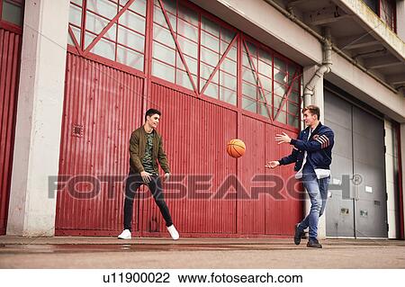 Stock Image - Two young men playing basketball in urban area, Bristol, UK. Fotosearch