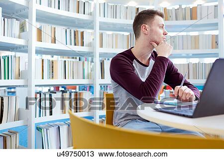 Stock Image - University student day-dreaming in library. Fotosearch