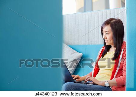 Stock Image - University student using laptop in modern cubicle. Fotosearch