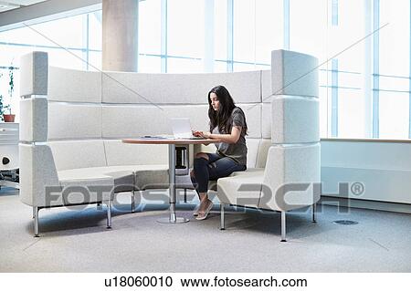 Stock Image - University student working in modern seating area. Fotosearch