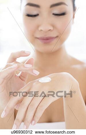 Stock Image - Woman applying cream to hand. Fotosearch