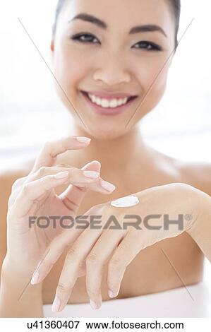 Stock Photo - Woman applying cream to hand. Fotosearch