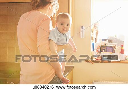 Woman carrying baby son in arms in kitchen View Large Photo Image Stock Photograph - Woman carrying baby son in arms in kitchen. Fotosearch