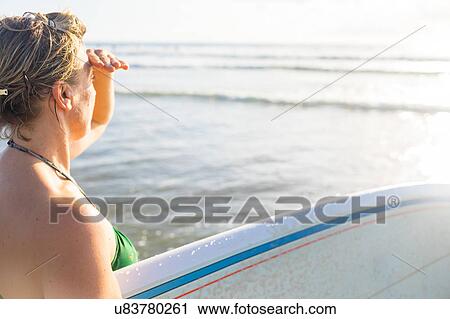 Woman carrying surfboard looking out to sea from beach, Nosara, Guanacaste Province, Costa Rica View Large Photo Image Stock Image - Woman carrying surfboard looking out to sea from beach, Nosara, Guanacaste Province, Costa Rica. Fotosearch