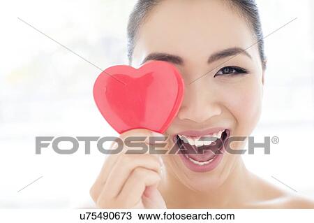 Stock Image - Woman covering eye with heart. Fotosearch