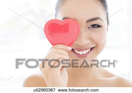 Stock Photo - Woman covering eye with heart. Fotosearch