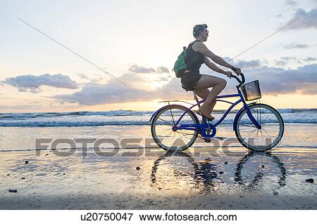 Woman cycling on beach at sunset, Nosara, Guanacaste Province, Costa Rica View Large Photo Image Stock Photo - Woman cycling on beach at sunset, Nosara, Guanacaste Province, Costa Rica. Fotosearch