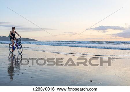 Woman cycling on beach at sunset, Nosara, Guanacaste Province, Costa Rica View Large Photo Image Stock Photograph - Woman cycling on beach at sunset, Nosara, Guanacaste Province, Costa Rica. Fotosearch