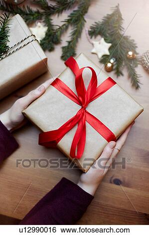 Woman holding Christmas gift tied with red bow, close-up View Large Photo Image Stock Photograph - Woman holding Christmas gift tied with red bow, close-up. Fotosearch