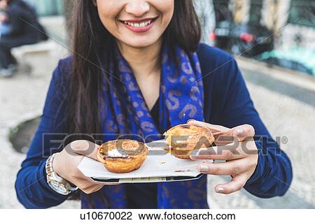 Stock Image - Woman holding pastel de nata, Lisbon, Portugal. Fotosearch